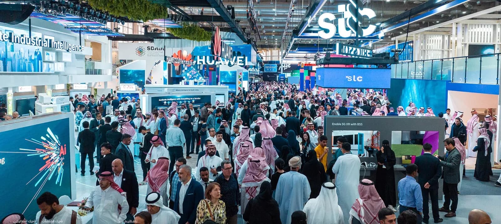 قاعة معرض تقني في الرياض بأجنحة تعلوها شاشات كبيرة وزوار يملؤون الممرات