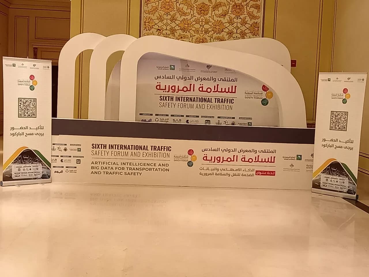 خلفية الملتقى والمعرض الدولي السادس للسلامة المرورية بأقواس بيضاء ولوحات تعريفية قائمة